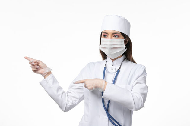 病毒正面图女医生身穿白色无菌医疗服 带口罩 因白墙上冠状病毒病冠状病毒-大流行病毒病套装冠状病毒防护人