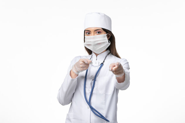 听诊器正面图女医生身穿白色无菌医疗服 带口罩 因白墙上有冠状病毒病冠状病毒-大流行性疾病套装冠状病毒冠状病毒防护