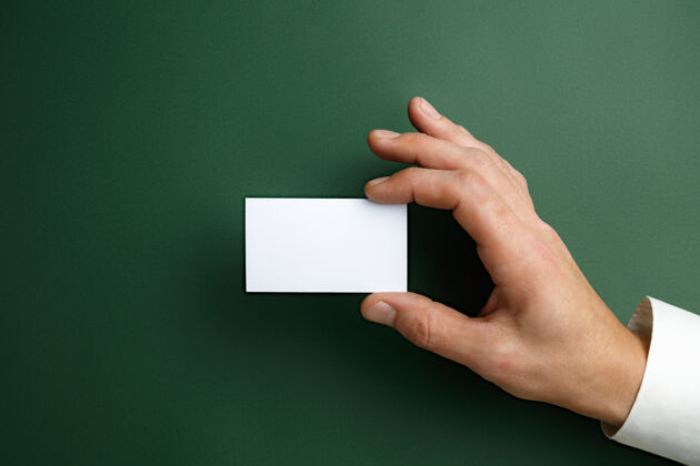 营销男性手拿一张空白名片放在绿色的墙上 用于文字或设计空白信用卡模板用于联系或在商业 金融 办公室使用复制空间问候语人工人