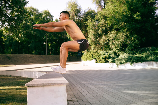 力量一个肌肉发达的男运动员在公园里锻炼体操 训练 健身锻炼柔韧性夏日城市在阳光明媚的日子里在太空场上动作人活跃