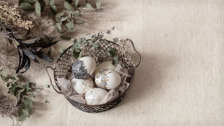 构图漂亮的复活节彩蛋放在一个用干花装饰的篮子里复活节快乐节日静物装饰