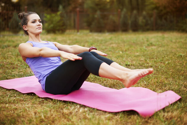 人体年轻女子在公园做瑜伽良好的伸展运动有助于避免肌肉酸痛运动服休息伸展