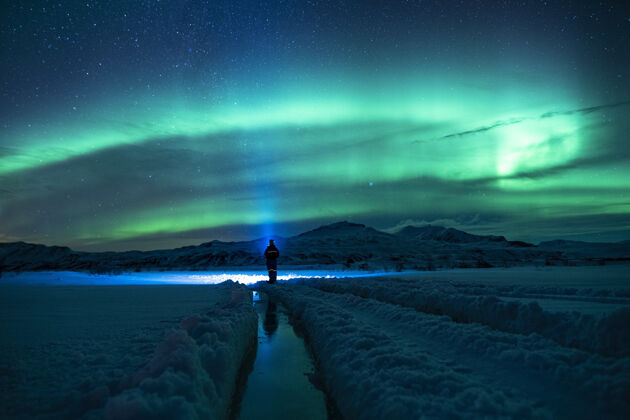自然站在雪地上的人在绿色的天空下冰户外冰岛