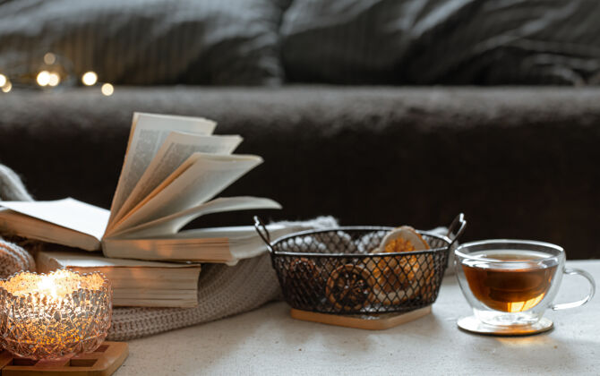 茶静物与一杯茶 书籍和燃烧的蜡烛在一个美丽的烛台家居舒适的概念细节烛台玻璃
