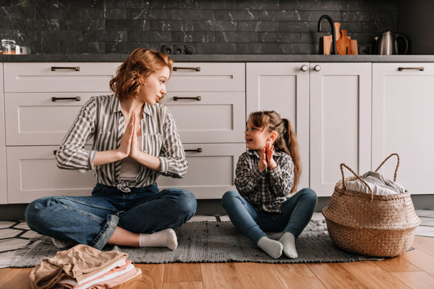 生活方式穿着条纹衬衫的女人正坐在地板上 教她的女儿如何冥想童年女人肖像