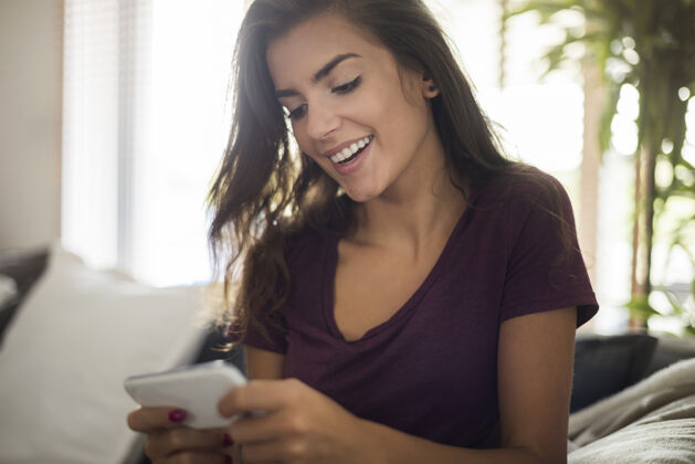 享受家里有智能手机的快乐美女牙齿微笑女人青年文化