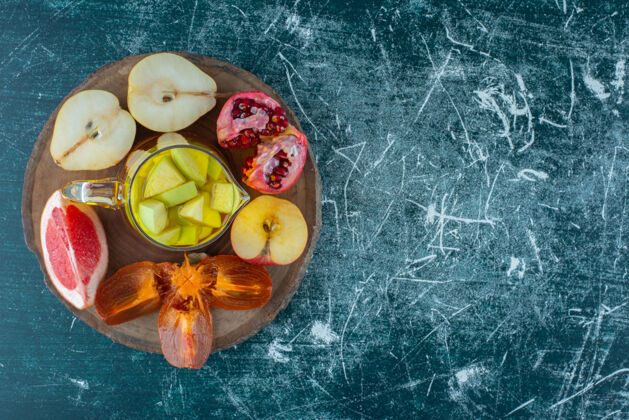 牙套各种各样的水果片放在一块板上 天然果汁放在一瓶咖啡汁里 苹果放在蓝色的背景上高质量的照片美味营养柿子