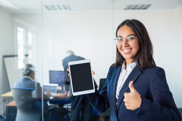 领导快乐的办公室女士展示空白的平板电脑屏幕 做着喜欢的手势 看着相机微笑复制空间沟通和广告理念专业讨论行政