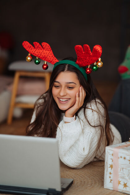 礼物在家里庆祝圣诞节期间 一只雌性的鹿角微笑着用笔记本电脑和网友聊天圣诞节新的季节