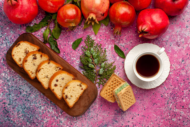 木块顶视图新鲜的红石榴与切片蛋糕和华夫饼在粉红色的表面面包石榴顶部