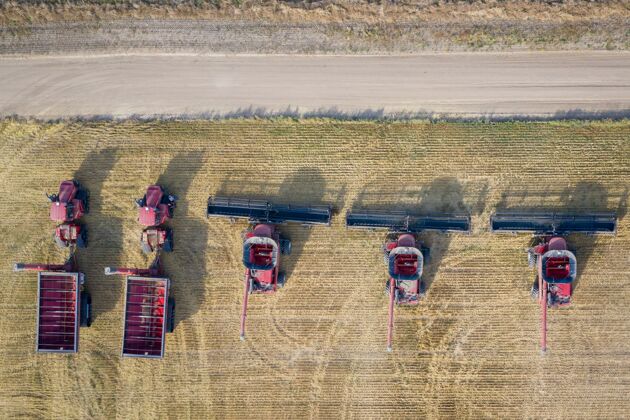 生产空中拍摄的联合收割机在农田在白天卡车田地工作