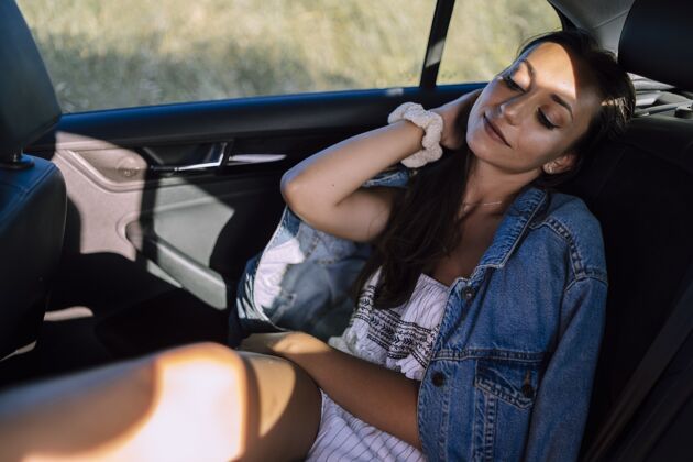 阳光一个美丽的年轻白人女性在一个领域的汽车后座摆姿势的水平镜头交通女性成人