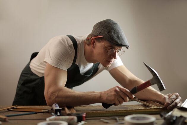 块一个戴着白色安全帽的木匠正在用锤子和螺丝钉修理一张木桌男修理手