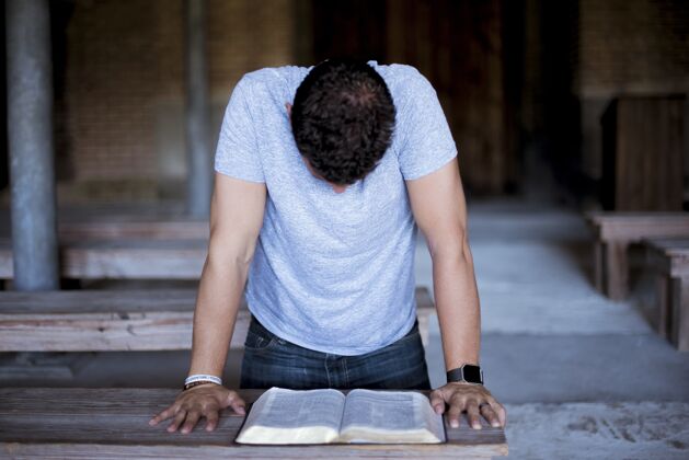 年轻人一个男人在木桌上读圣经的特写镜头宗圣经