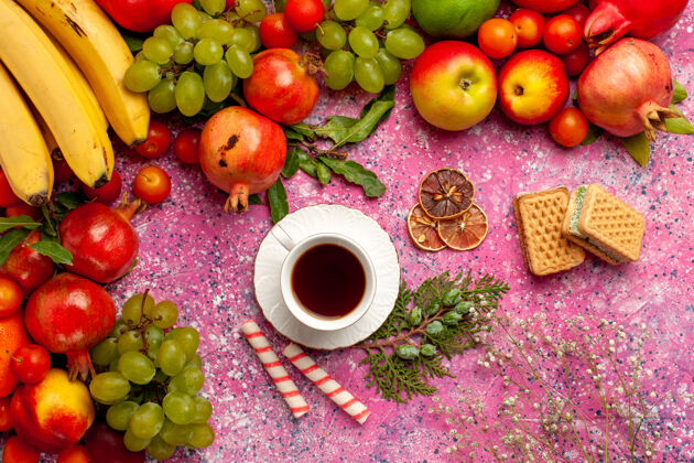 水果顶视图新鲜水果组成彩色水果与华夫饼和一杯茶在粉红色的表面华夫饼树新鲜