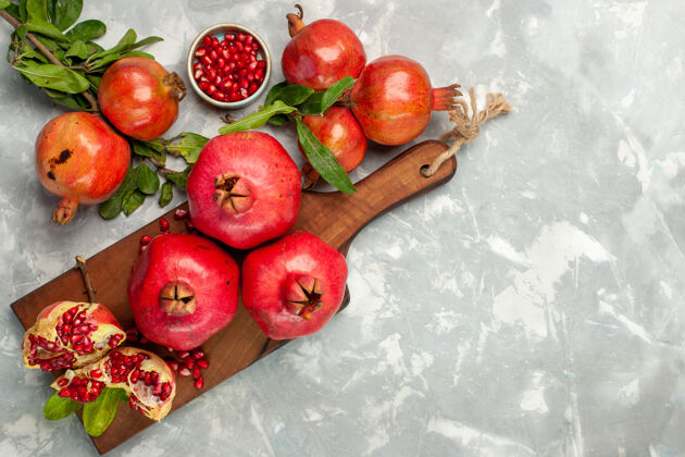 顶部在浅白的桌子上俯瞰新鲜的红石榴 酸甜的水果生的西红柿苹果