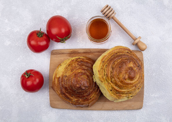 球队阿塞拜疆传统糕点gogal的俯视图 木质厨房板上放着蜂蜜 玻璃罐上放着新鲜的西红柿 背景是白色的成功木板木材