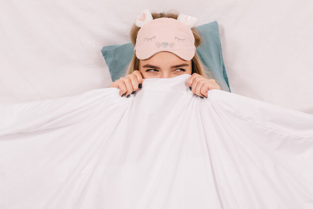 模型戴着睡眠面具的可爱女人在床上摆姿势美女睡眠枕头