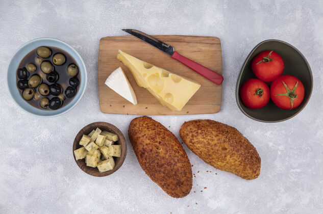 西红柿木制菜板上奶酪的俯视图 白色背景上有小刀 肉饼 西红柿和橄榄白色金色乡村风味