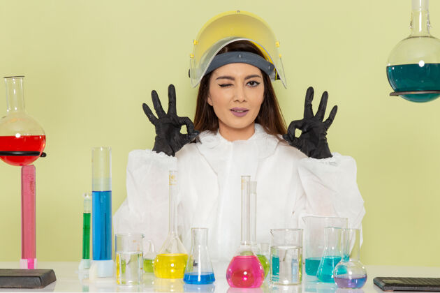 化学正面图身着特殊防护服的年轻女化学家在浅绿色墙壁上工作化学工作科学实验室化学家西装年轻人