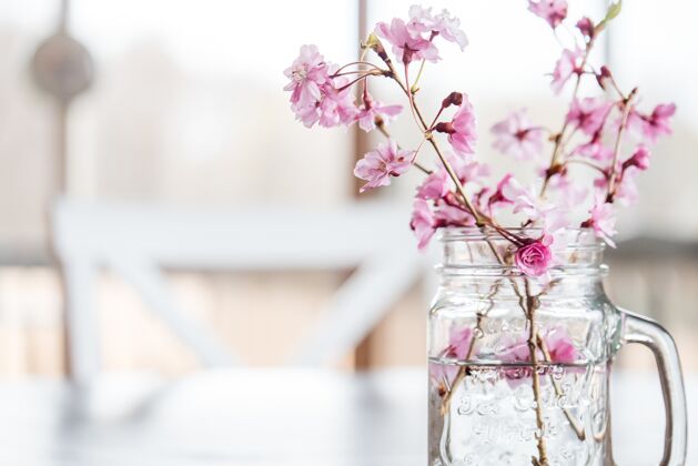 花樱桃花和树枝在一杯清水下放在桌上的灯下植物房子特写
