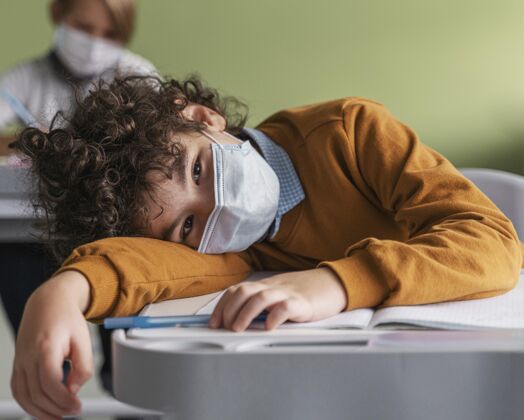 面罩戴着医用口罩的孩子在学校上课很无聊孩子知识学习