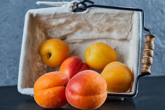 好吃把油桃和杏子放在蓝色的篮子里美味桃子多汁