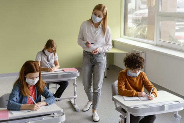 学习戴着医用口罩的孩子在学校和老师一起学习学习教师流行病