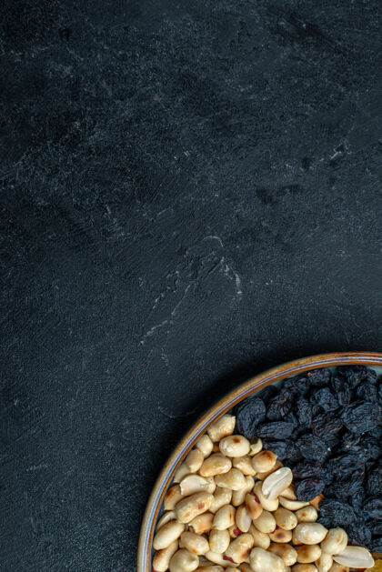 小吃顶视图榛子和葡萄干等坚果上的深灰色背景坚果零食干果照片烤箱背景视图