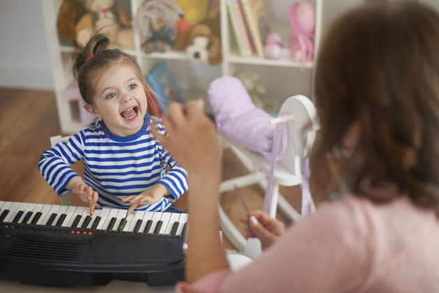 教学妈妈和女儿在演奏音乐和唱歌可爱快乐家庭室内