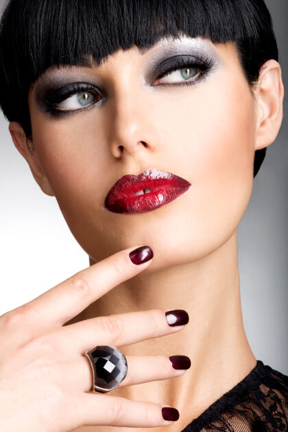 红葡萄酒一张长着漂亮黑指甲和性感红唇的女人的脸一头黑发的时尚模特姿势肖像漂亮