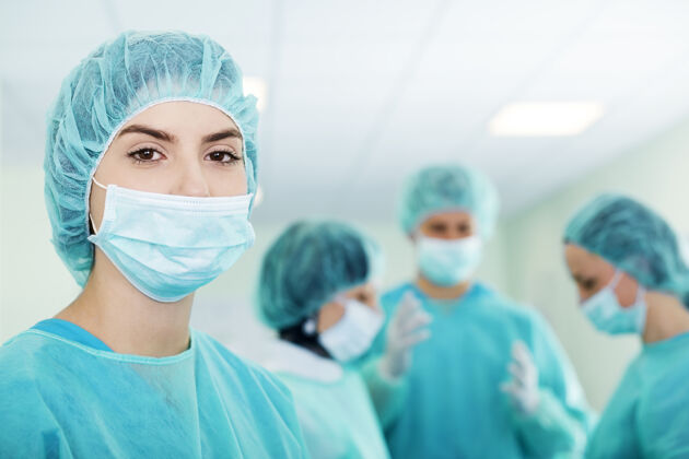 医院年轻的女外科医生在手术前带着医疗队在后面实验服卫生团队合作