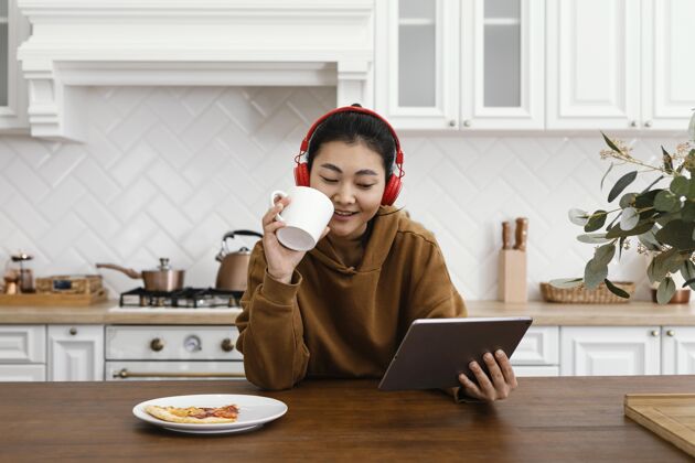 女性在平板电脑上看视频喝咖啡的女人房子年轻休闲