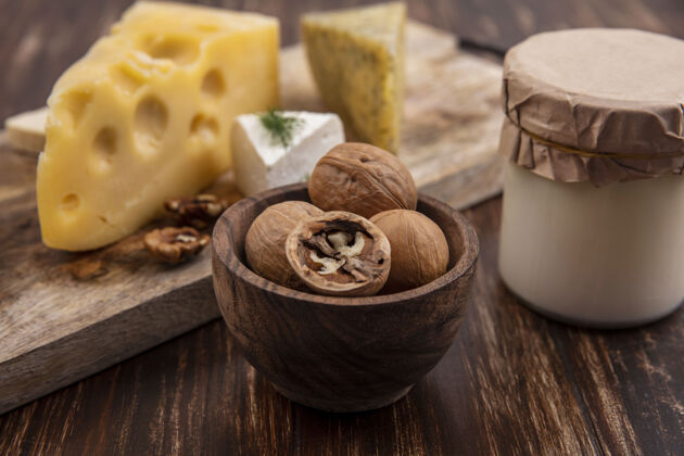 酸奶侧视图核桃与各种奶酪的立场上与酸奶在一个木桶的背景风景罐子奶酪
