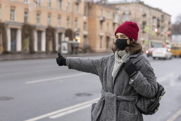 病毒戴着医用口罩的女人在城里搭便车流行病人类预防措施