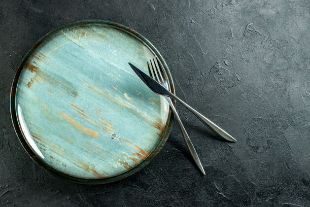 容器俯视图圆碟钢叉和餐刀上的黑色桌子与自由的地方过滤器刀视图