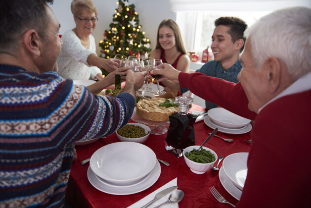 抱着为圣诞节的家庭时间干杯吃饭喝酒家庭
