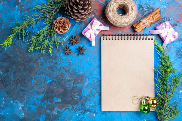 肉桂俯视笔记本上的圣诞球松树枝桂枝八角干柠檬片在蓝色表面自由的地方茴香顶圣诞节