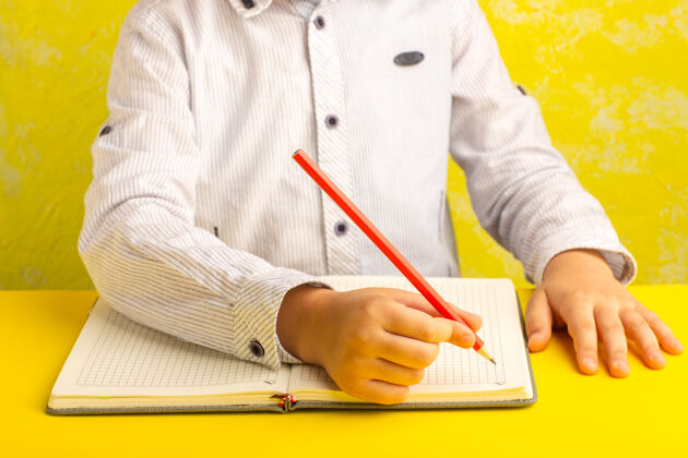 手正面图：小孩在黄色的表面上写字和画画前面孩子办公室