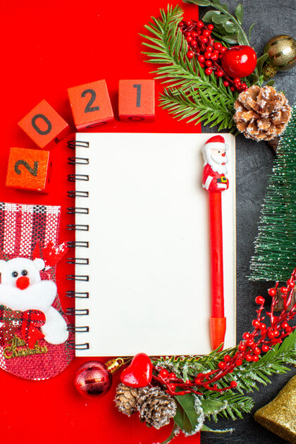 花卉垂直视图螺旋笔记本装饰配件杉木枝xsmas袜子数字在一个红色的餐巾和圣诞树在黑暗的背景餐巾袜子螺旋笔记本