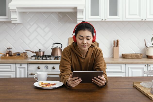 年轻女人在平板电脑上听在线视频房子家享受