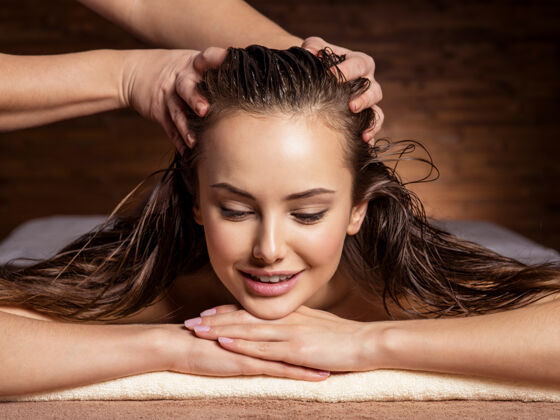 头发护理按摩师在spa沙龙为一位女士按摩头部和头发治疗成人沙龙