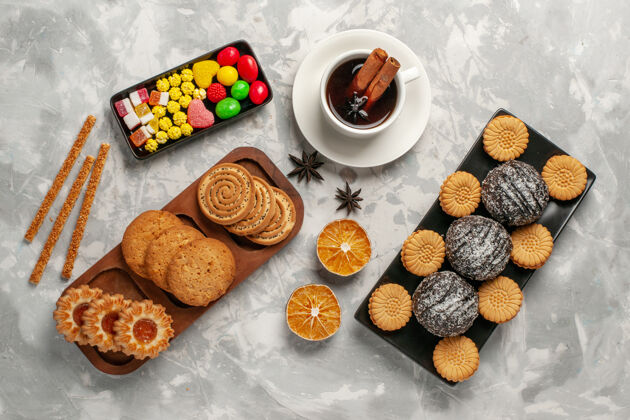 饼干俯瞰巧克力蛋糕与饼干糖果和一杯茶在白色的表面糖饼干烘焙