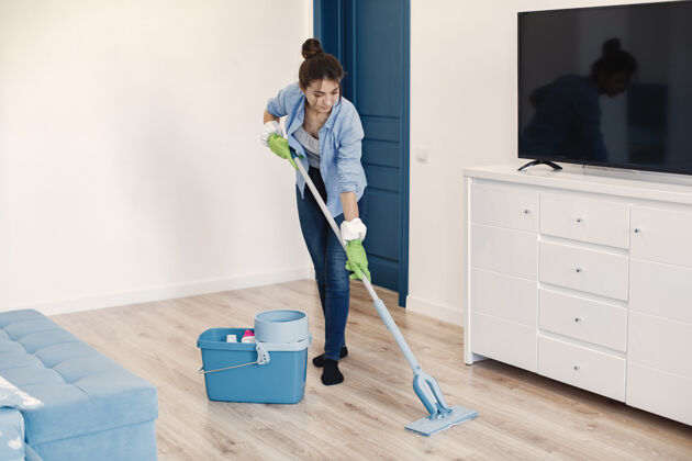 女性在家工作的家庭主妇穿蓝色衬衫的女士清洁地板的女士家务公寓洗涤剂