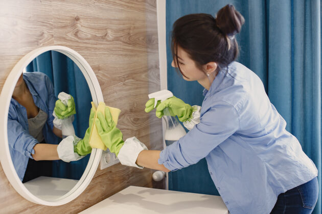 服务在家工作的家庭主妇穿蓝色衬衫的女士清洁镜子的女士女室内洗涤剂