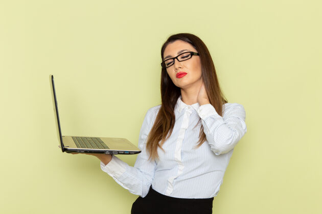 人穿着白衬衫和黑裙子的女上班族在绿墙上拿着笔记本电脑的正视图笔记本电脑微笑商务