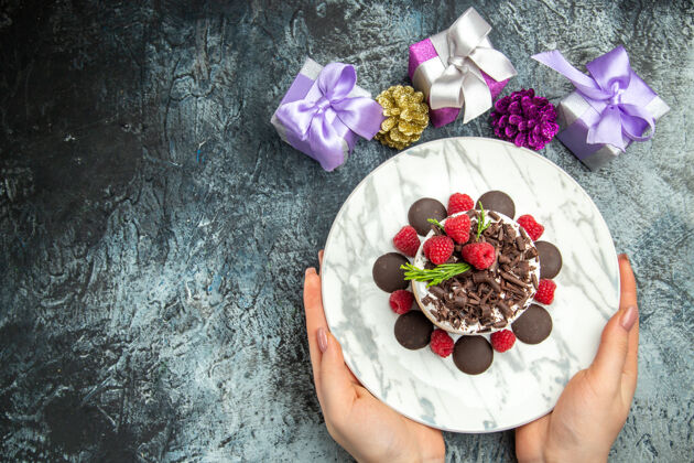 甜点俯瞰巧克力芝士蛋糕椭圆形盘子在妇女手中圣诞礼物在灰色表面免费的地方地方女士盘子