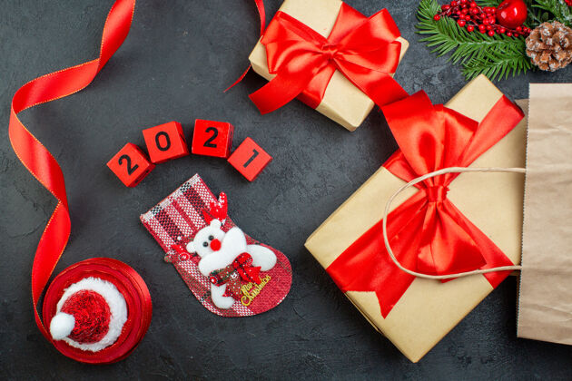 顶部圣诞气氛的顶视图与美丽的礼物杉木枝针叶树圆锥红丝带和数字圣诞老人帽xsmas袜子在黑暗的背景帽子蝴蝶结视图