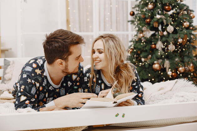 夏娃穿着圣诞老人装潢的人们穿着睡衣的男人和女人一家人在床上圣诞树卷发室内