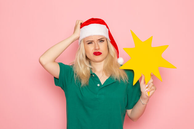 形象正面图年轻女性手持粉色墙壁上的黄色大人物度假照片新年快递员制服工作圣诞节漂亮肖像